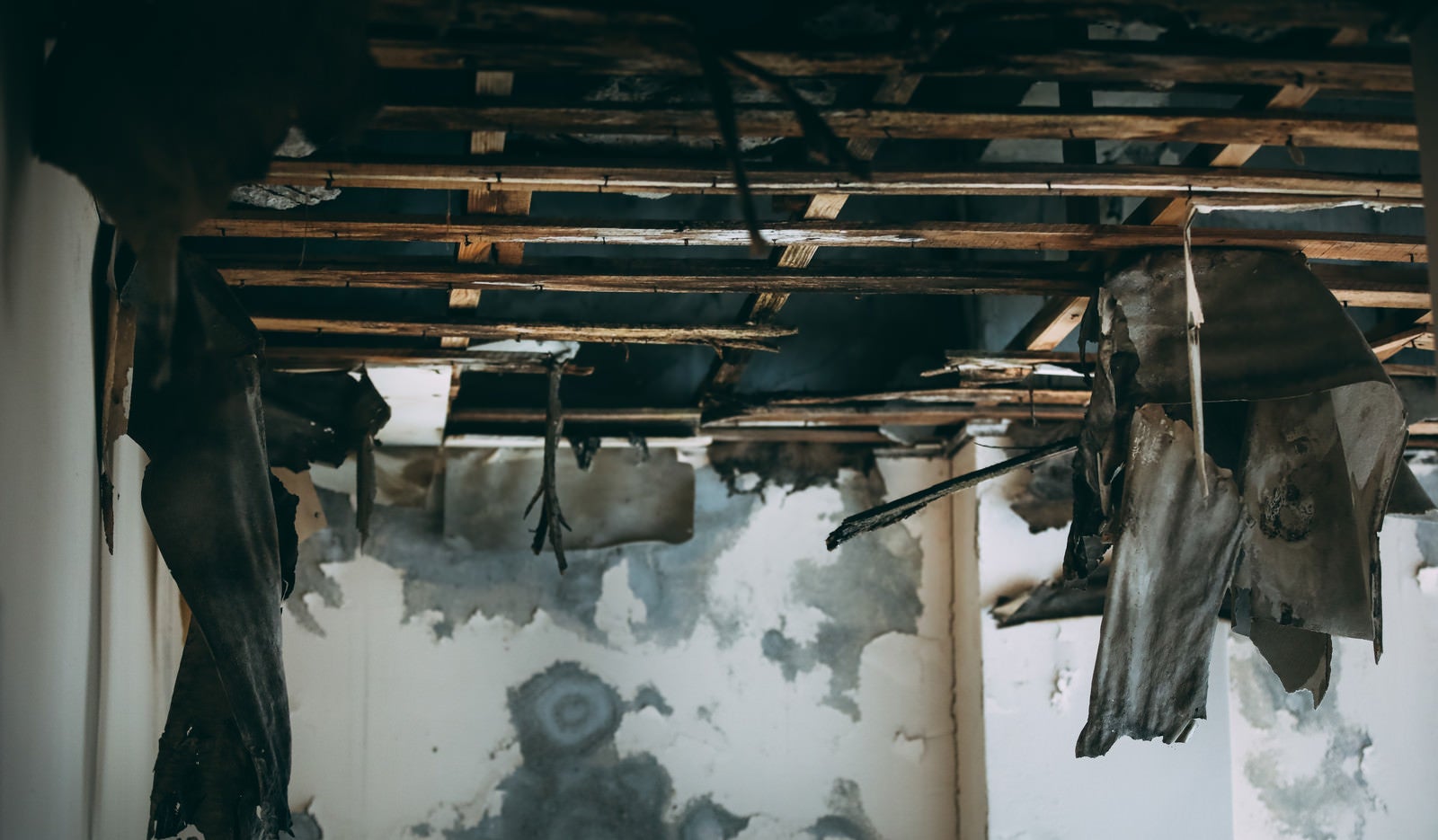 「崩れ落ちた天井から下がるすすけたカーテン」の写真