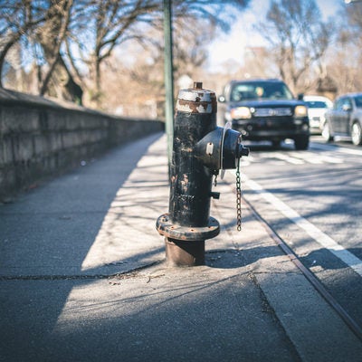 歩道に設置された錆び付く消火栓の写真