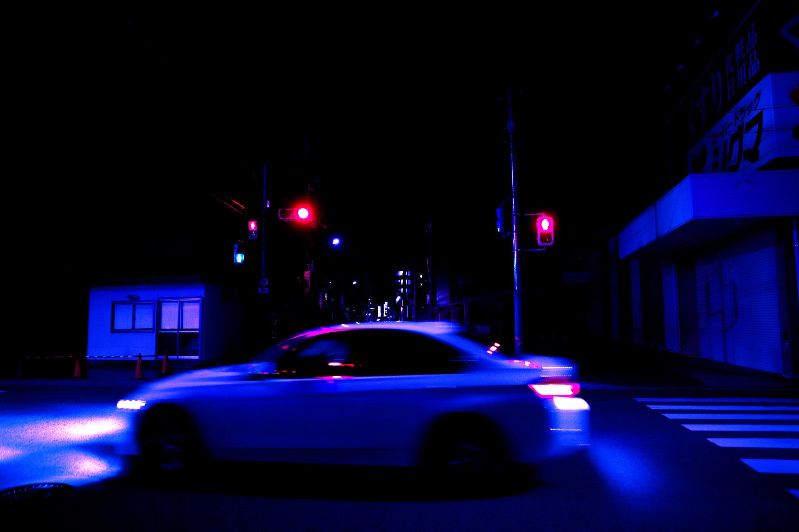 「深夜の交差点を走り去る自動車」の写真