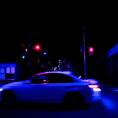 深夜の交差点を走り去る自動車の写真