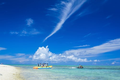 沖縄の海とバナナボートの観光客の写真