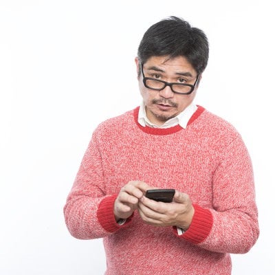 スマホアプリに困惑するメガネをかけた中年の父親の写真