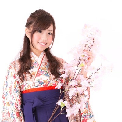 桜の枝と袴姿の女性の写真
