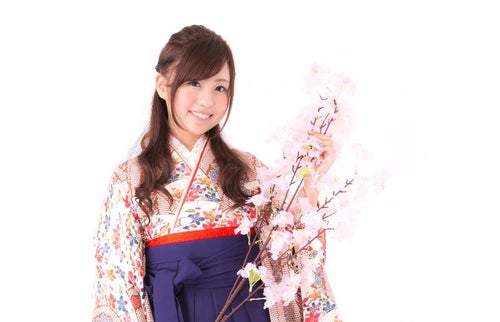 桜の枝と袴姿の女性の写真