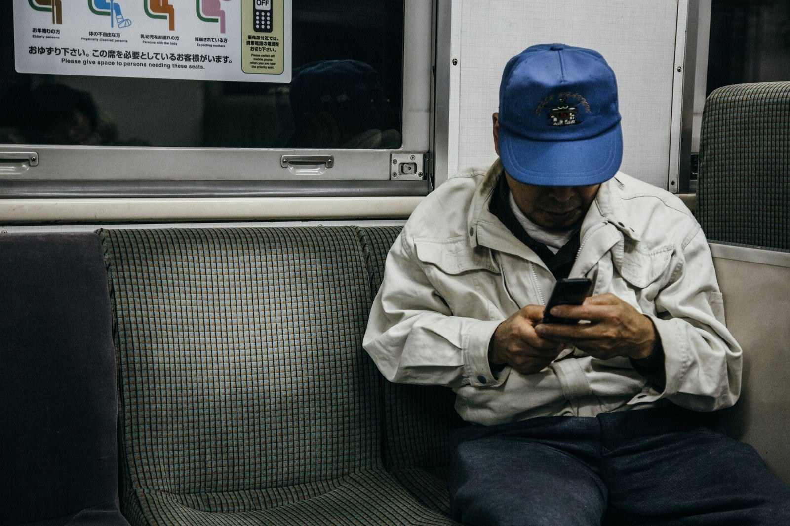 「ローカル線で帰宅する作業着姿の年配者」の写真