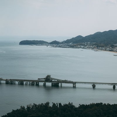 静かな海と工場を繋ぐ橋の写真