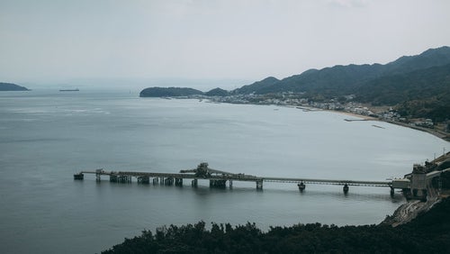 静かな海と工場を繋ぐ橋の写真