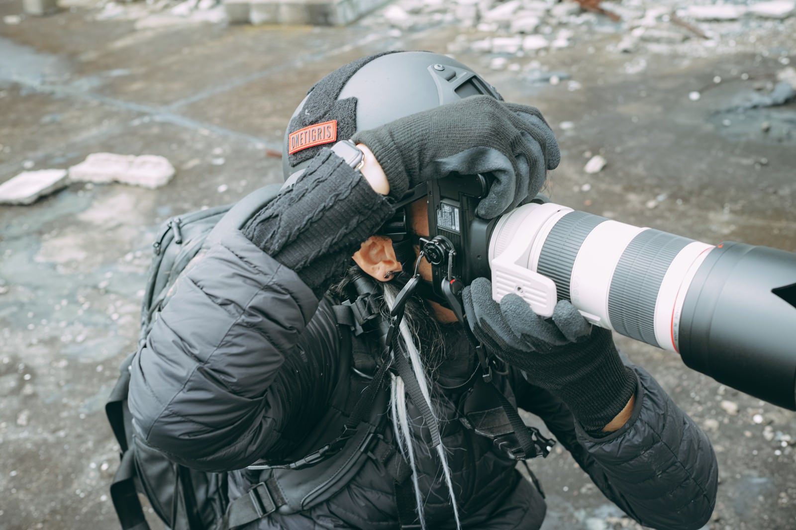 「ヘルメットを装着して危険地帯でカメラを構えるカメラマン」の写真［モデル：YAT］