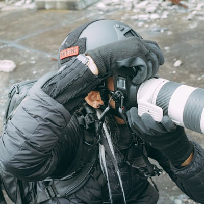 ヘルメットを装着して危険地帯でカメラを構えるカメラマンの写真