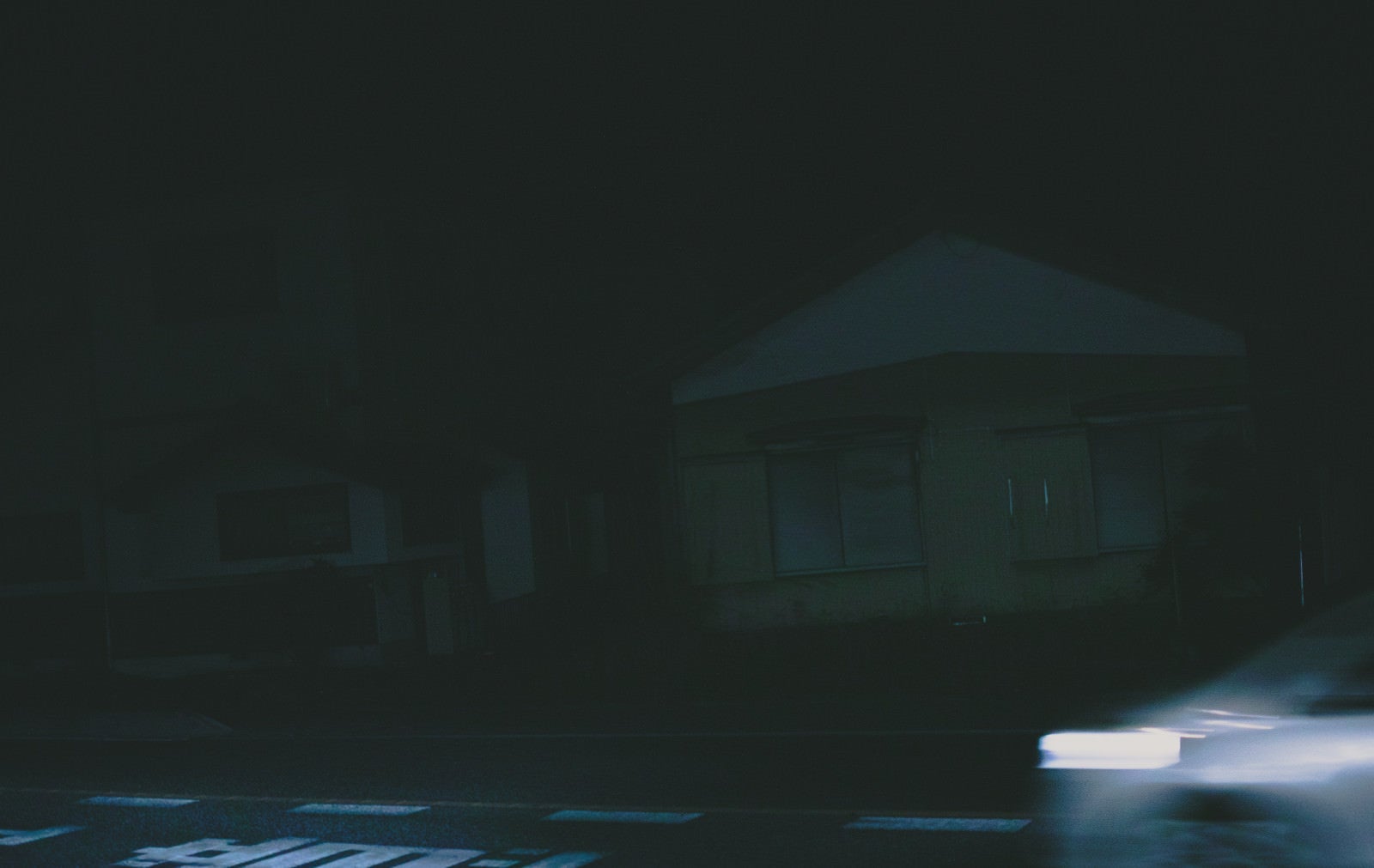 「深夜帯の民家前を走り去る車の残像」の写真