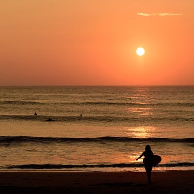 朝日に照らされる一宮海岸のサーファー達（千葉県一宮町）の写真