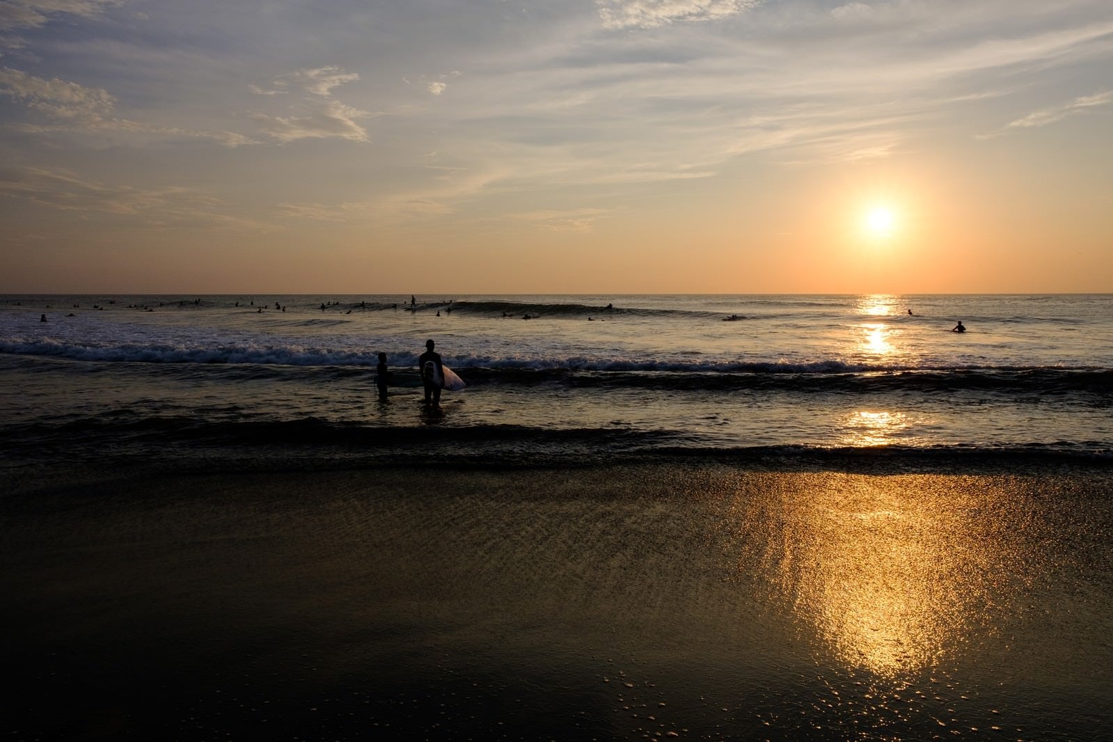 「朝日に照らされる引波の波打ち際とサーファー達（千葉県一宮町）」の写真