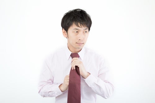 ネクタイを締める広告代理店勤務の新入社員の写真