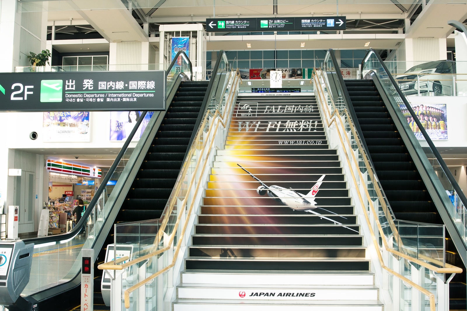 「搭乗手続きは2Fです。北九州空港玄関正面の階段」の写真