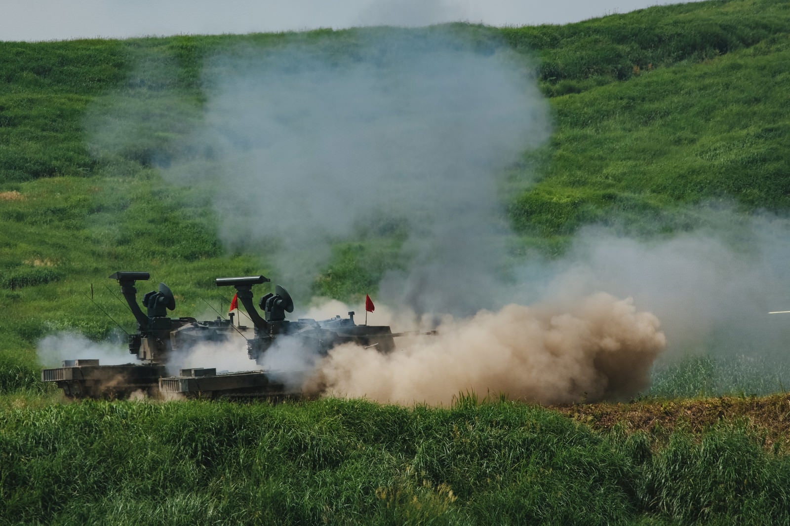 「87式自走高射機関砲の射撃で巻き上がる砂埃」の写真