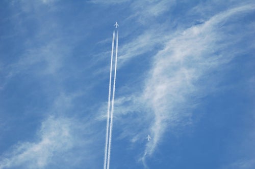 空に真っすぐ描かれた飛行機雲の写真