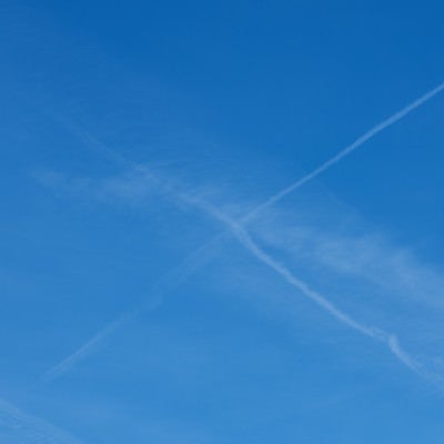 飛行機雲が交差して消えていくの写真