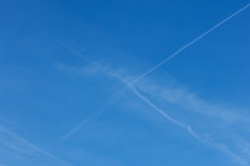 飛行機雲が交差して消えていくの写真