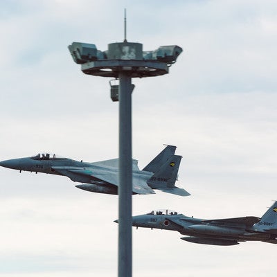 鉄塔被りの併走する戦闘機（F-15）の写真