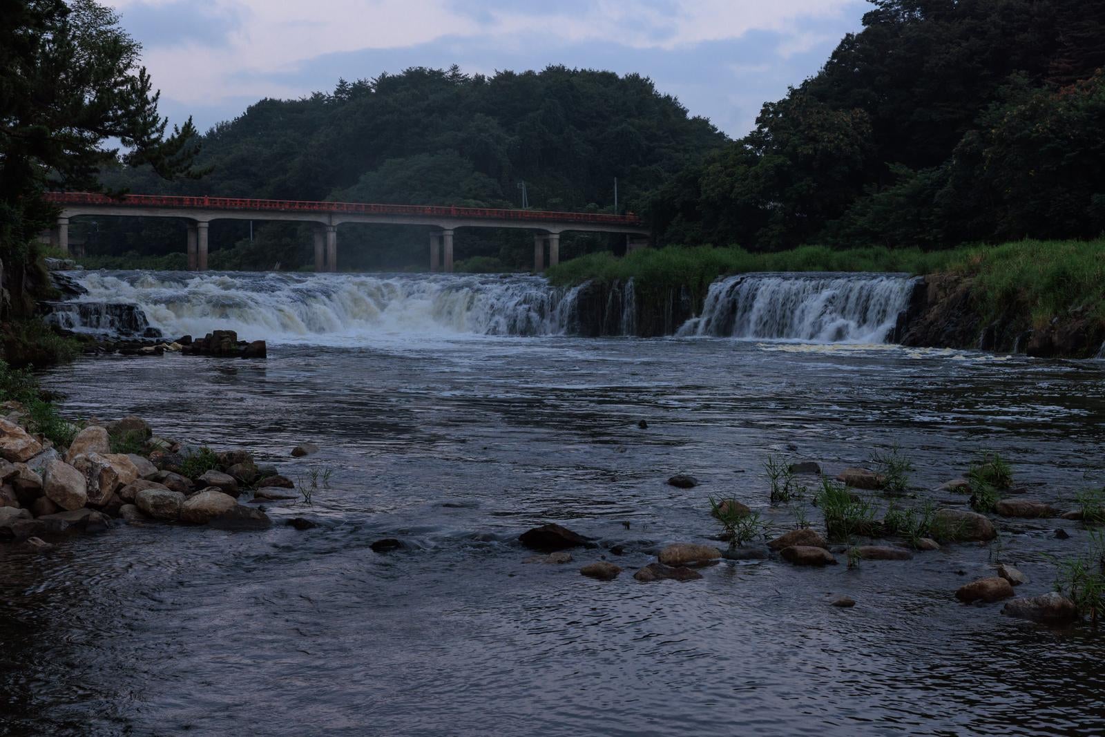 玉川村の乙字ヶ滝と赤い乙字橋、多段の滝が流れ落ちる河川景観