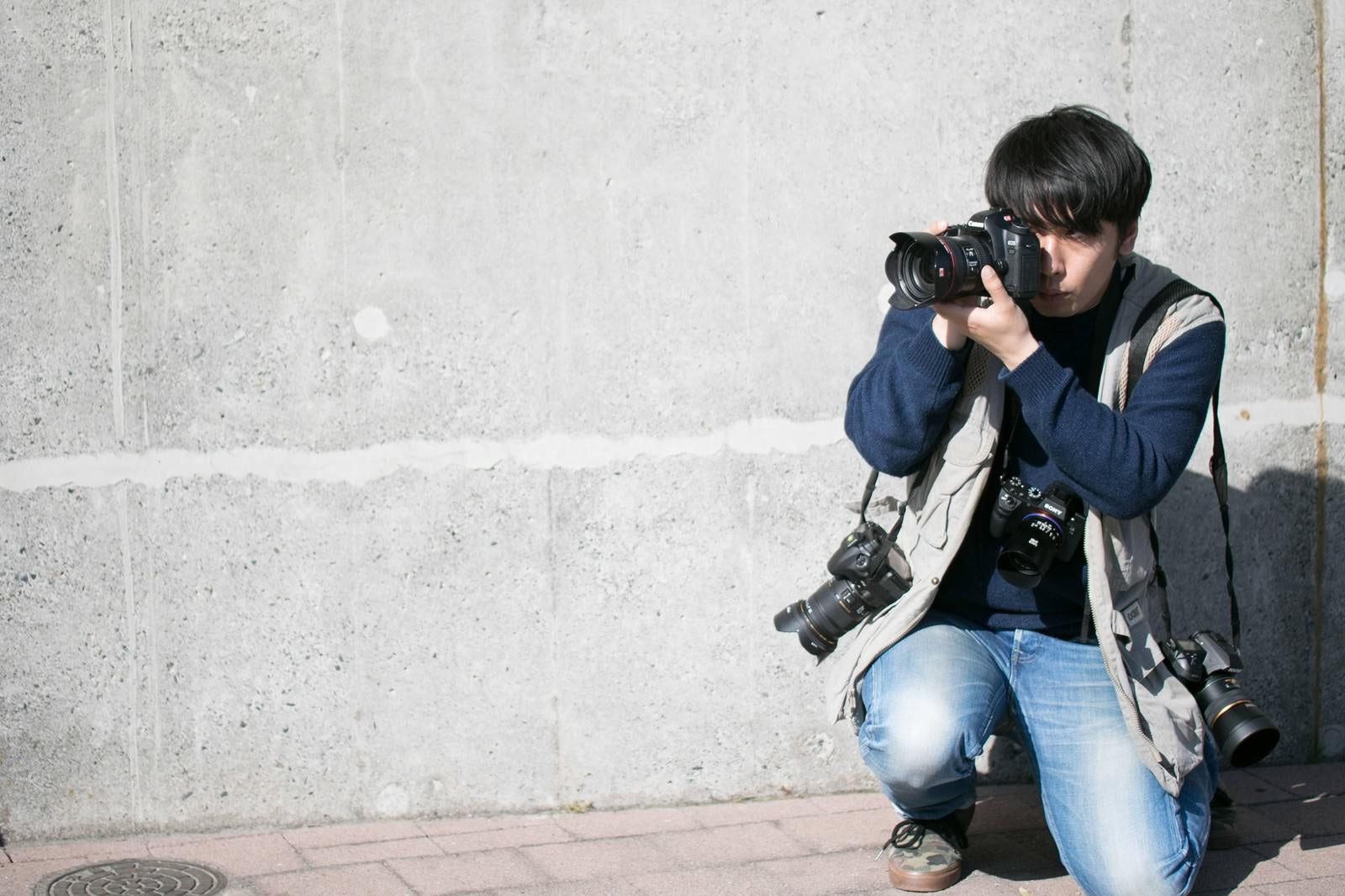 「肩にカメラをかける機材過多」の写真［モデル：大川竜弥］