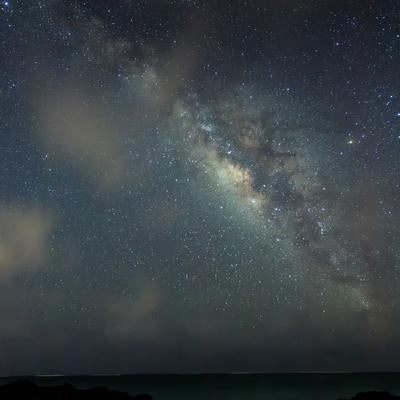 星々と天の川が輝く夜の海岸線の写真