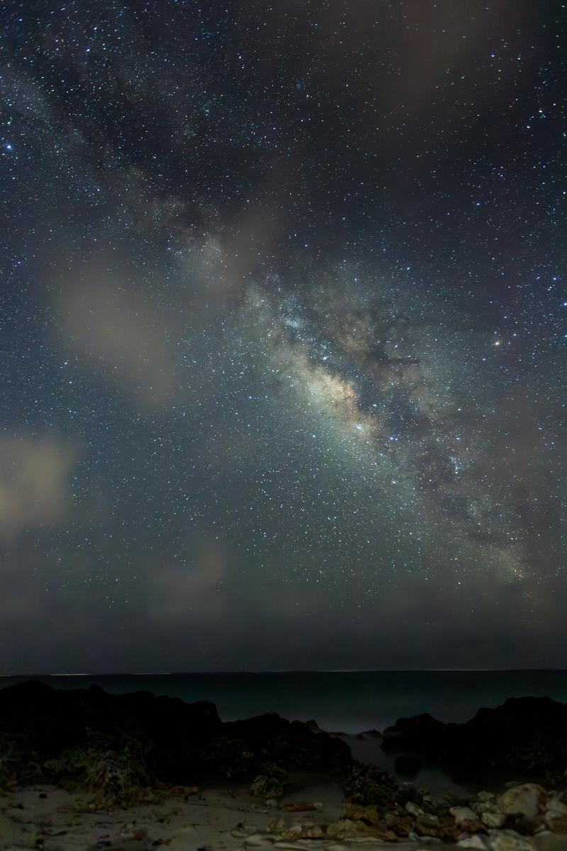 「星々と天の川が輝く夜の海岸線」の写真