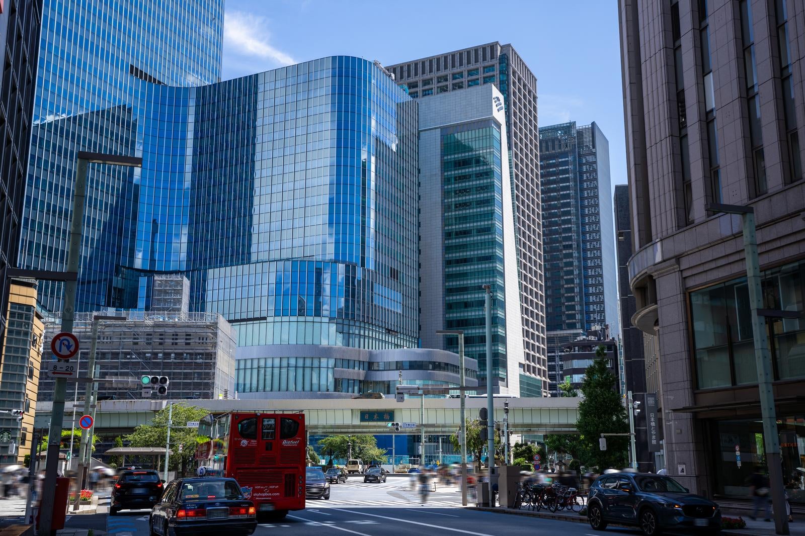 Street view of Nihonbashi (Nihonbashi) on a clear day with multiple high-rise office buildings lined up centered around a large blue and white architectural structure