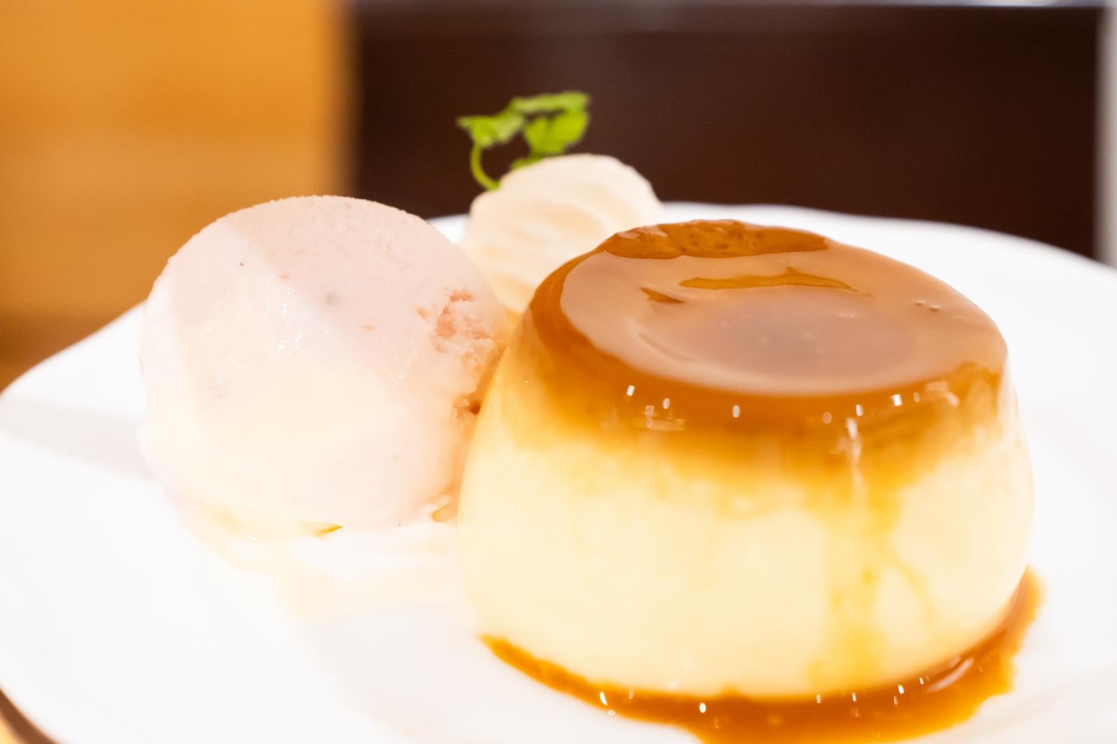 白い皿に盛り付けられたカラメルソースのカスタードプリンとアイスクリーム