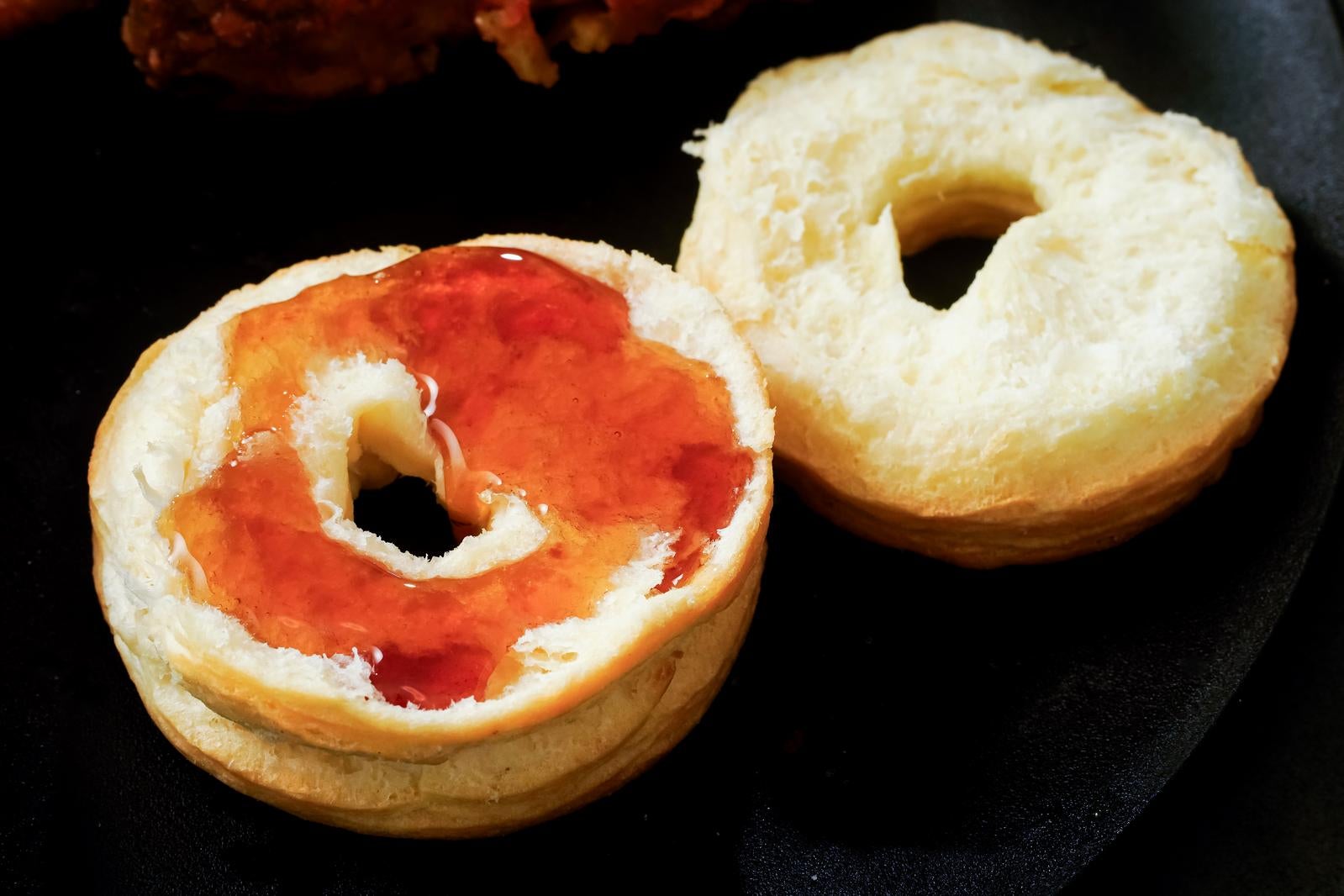 黒い背景の上に置かれたジャム塗りビスケットと白いドーナツ