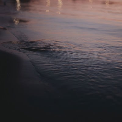 夕日を反射する波打ち際の写真