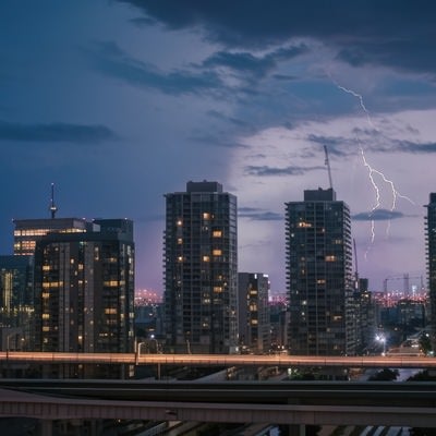 高層ビルが立ち並ぶ都会に雷雲の写真