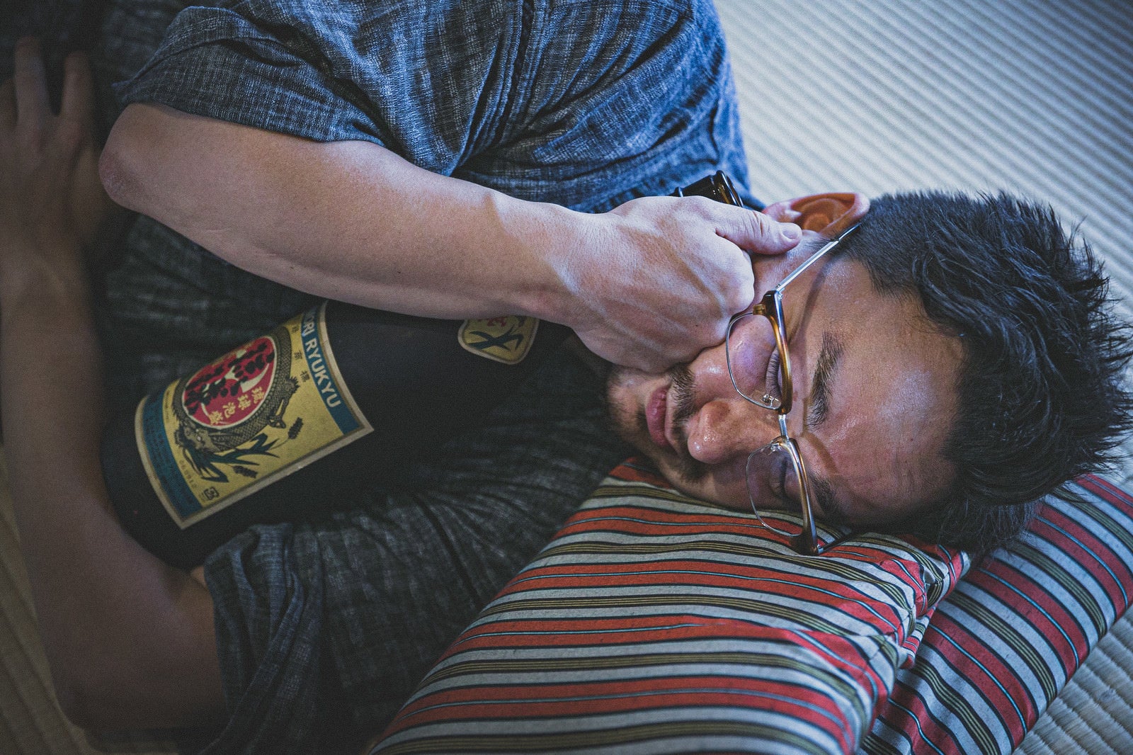 「日本酒の一升瓶を抱えて寝落ちする外国人」の写真［モデル：Max_Ezaki］