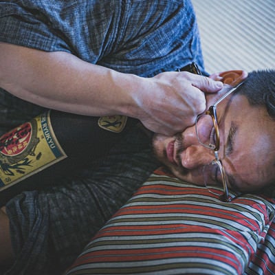 日本酒の一升瓶を抱えて寝落ちする外国人の写真