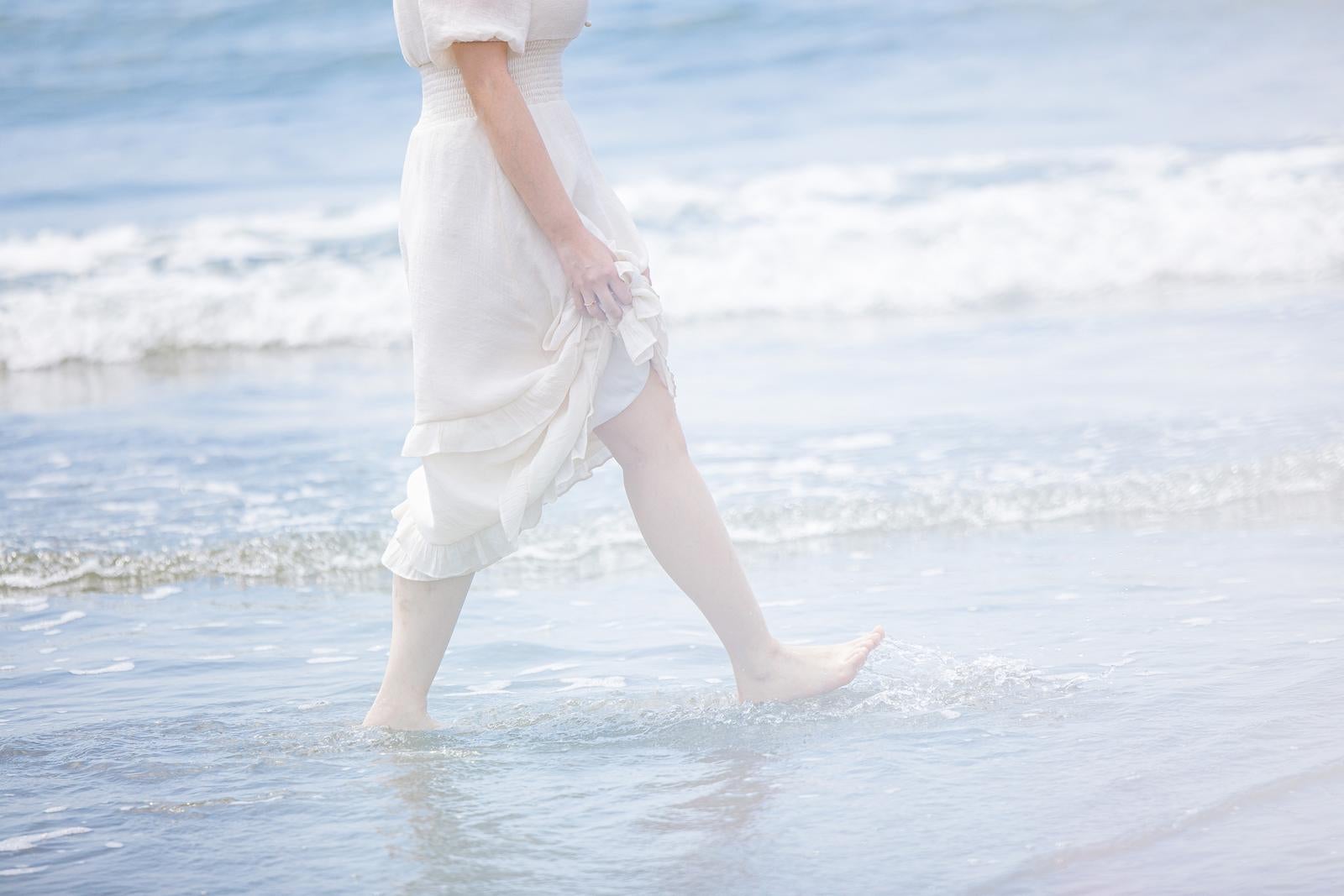 「岩井海岸の波打ち際を裸足で歩く女性の足元」の写真