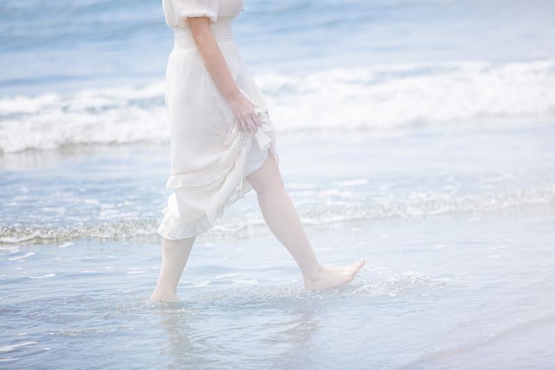岩井海岸の波打ち際を裸足で歩く女性の足元の写真