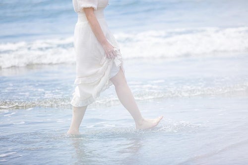 岩井海岸の波打ち際を裸足で歩く女性の足元の写真