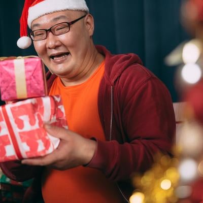サプライズでクリスマスプレゼントを受け取る男性の写真