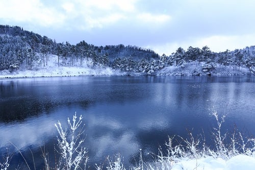 山間の沼と雪景色の写真