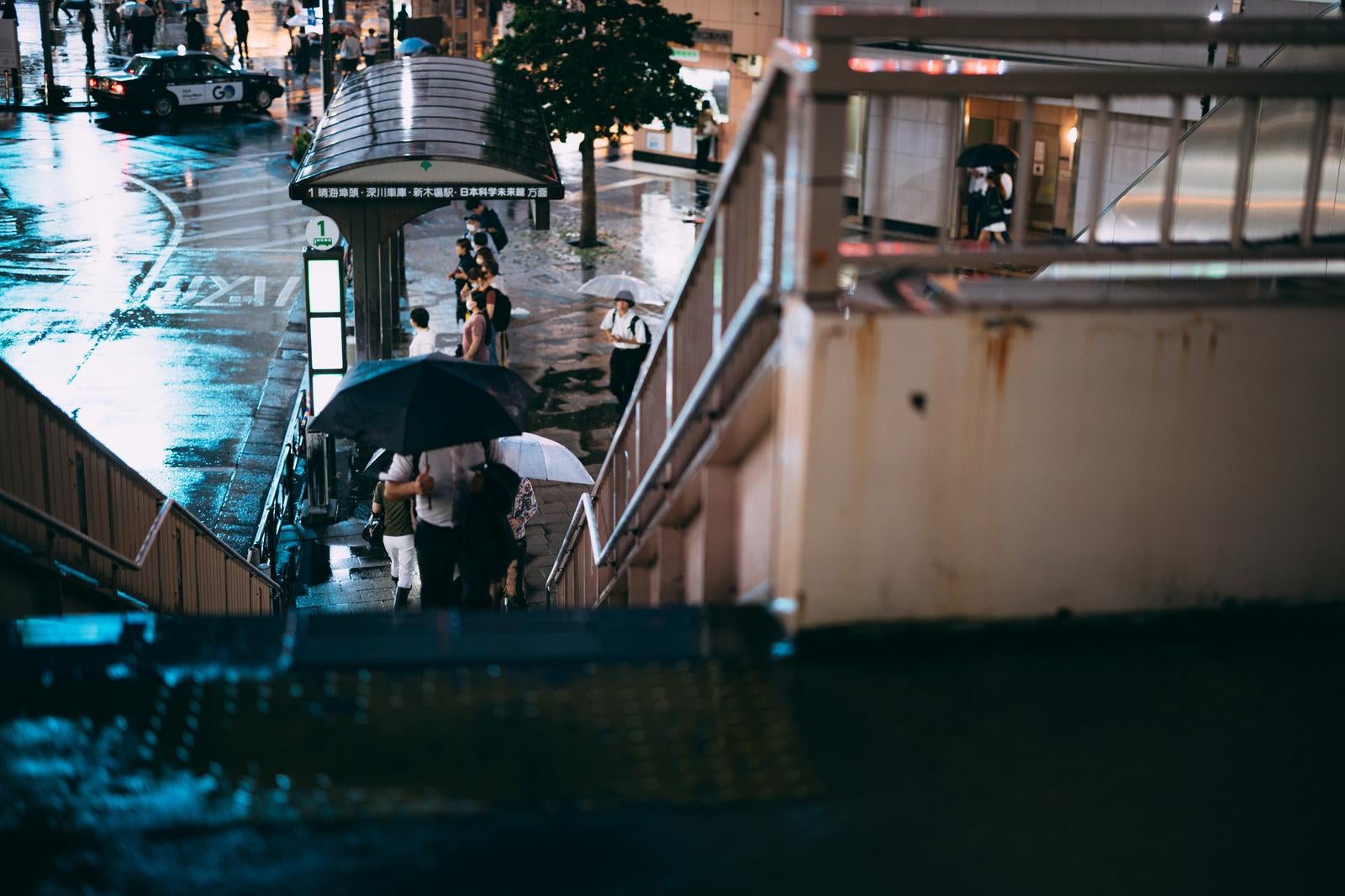 「雨上がりの歩道橋と傘を差して帰路につく歩行者」の写真