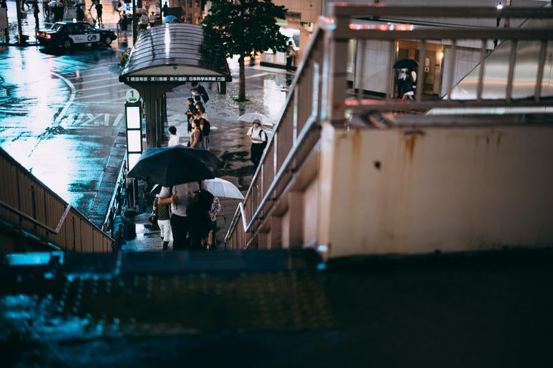 雨上がりの歩道橋と傘を差して帰路につく歩行者の写真