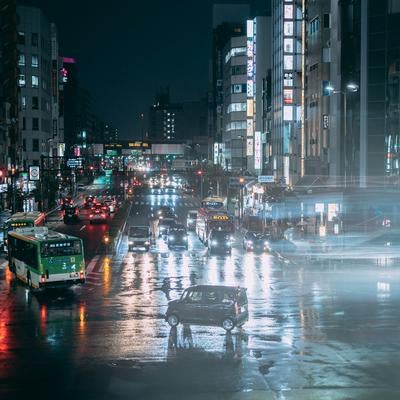 雨の日の夜交差点濡れた路面と車のライトの写真