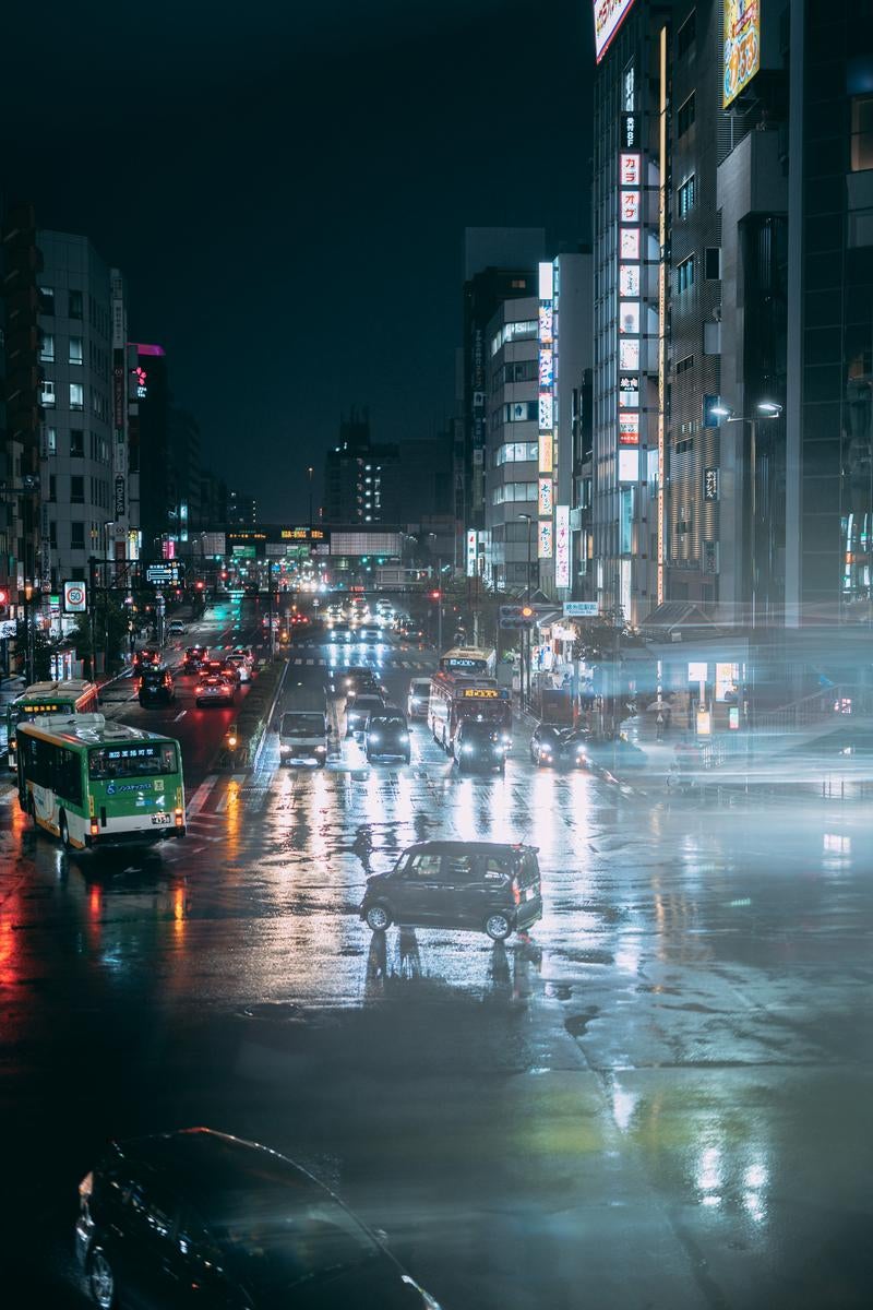 雨の日の夜交差点濡れた路面と車のライトの写真