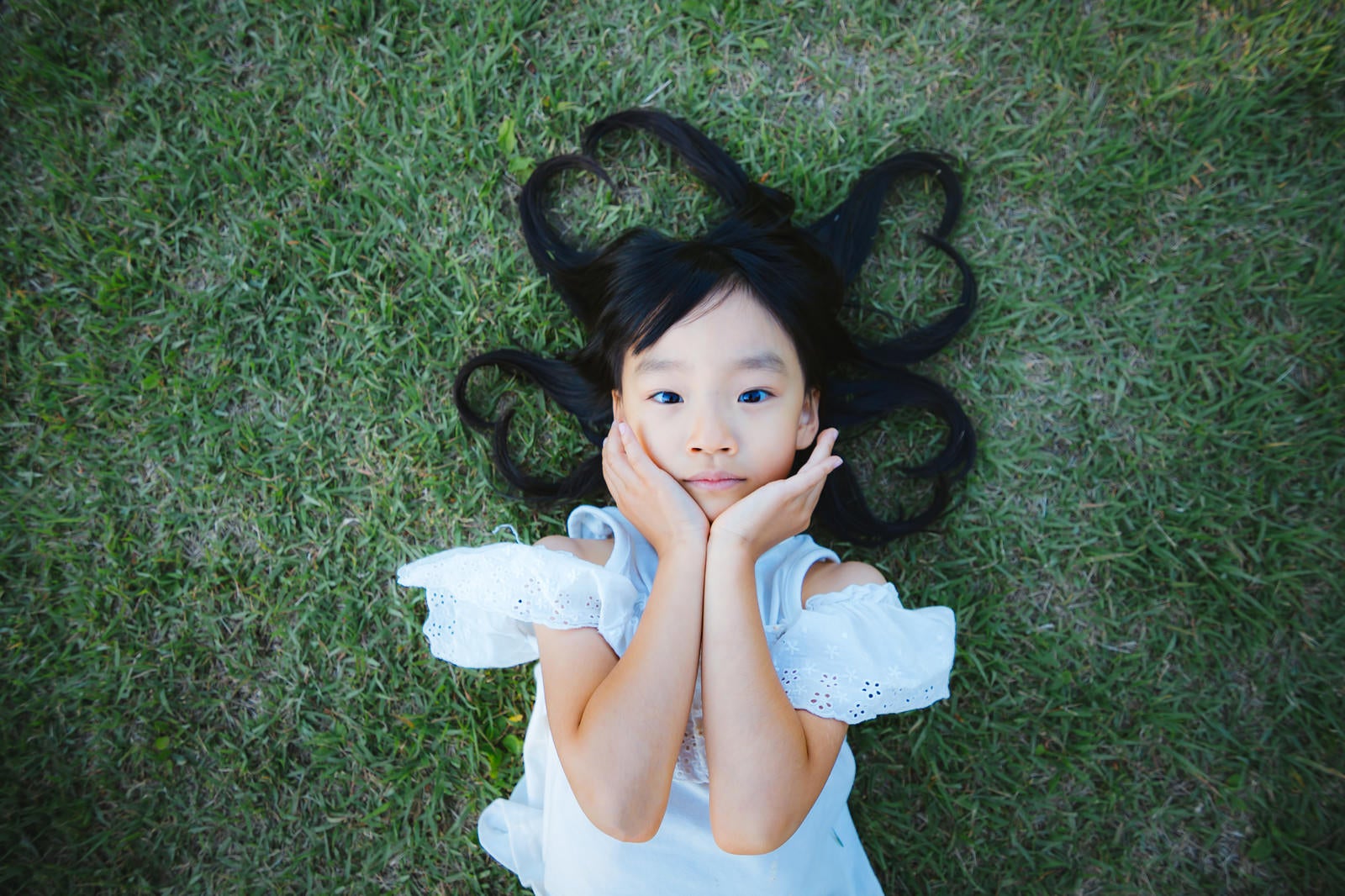 「芝生で寝転ぶ女の子（髪の毛ハート）」の写真［モデル：あんじゅ］