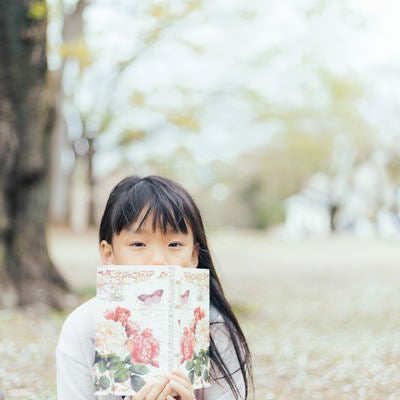 公園で洋書を広げる女の子の写真
