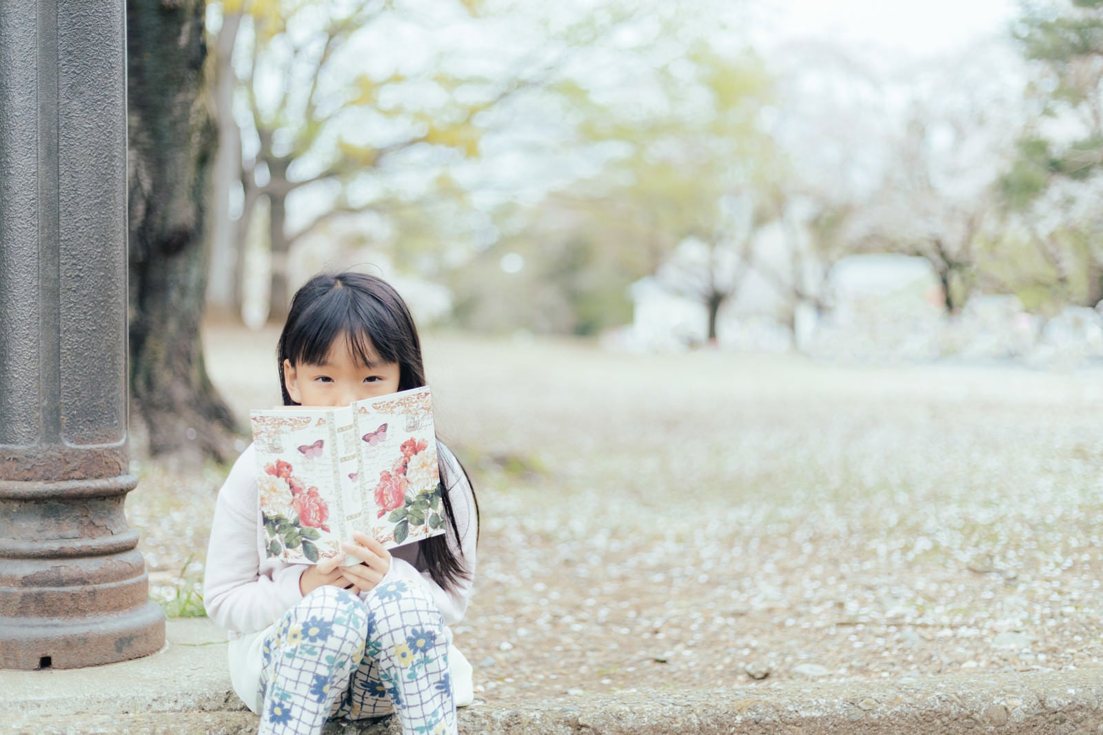 「公園で洋書を読む女の子」の写真［モデル：あんじゅ］