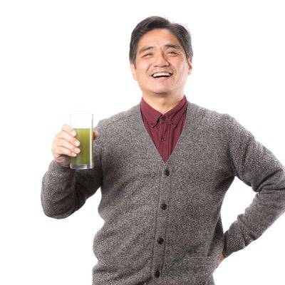 野菜不足を補う青汁を笑顔で紹介する中年男性の写真