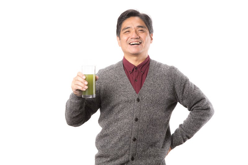 野菜不足を補う青汁を笑顔で紹介する中年男性の写真