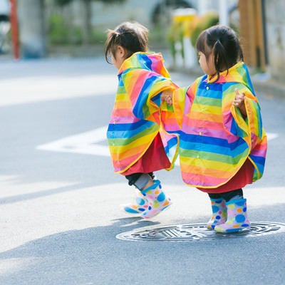 カラフル合羽で仲良く散歩する双子の写真