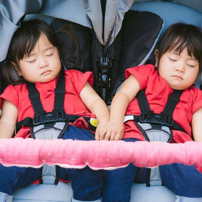 二人乗りベビーカーで爆睡中の双子姉妹の写真